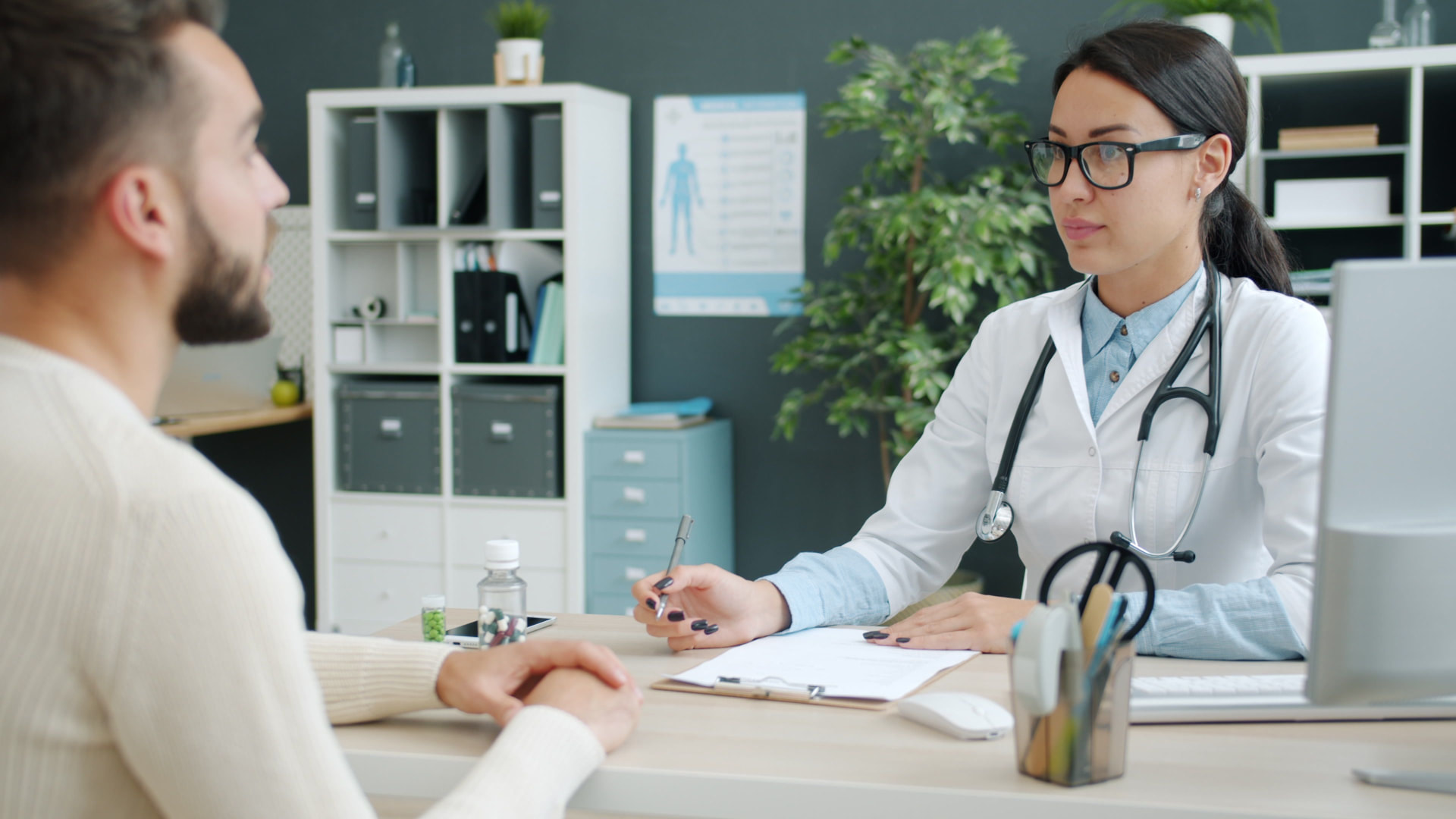 Ärztin im Sprechzimmer im Gespräch mit einem Patienten